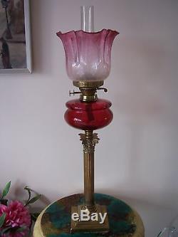 A Tall Victorian Cranberry Glass Oil Lamp And Shade With Brass Column Base